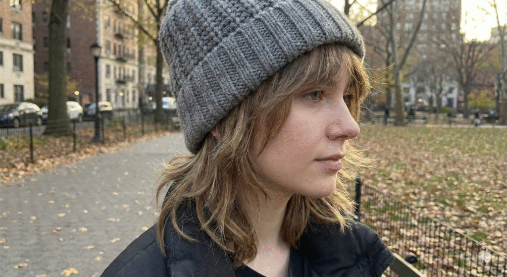 Woman wearing a beanie with the Reimagined Wolf Cut 2025 showing face-framing layers perfect for winter.